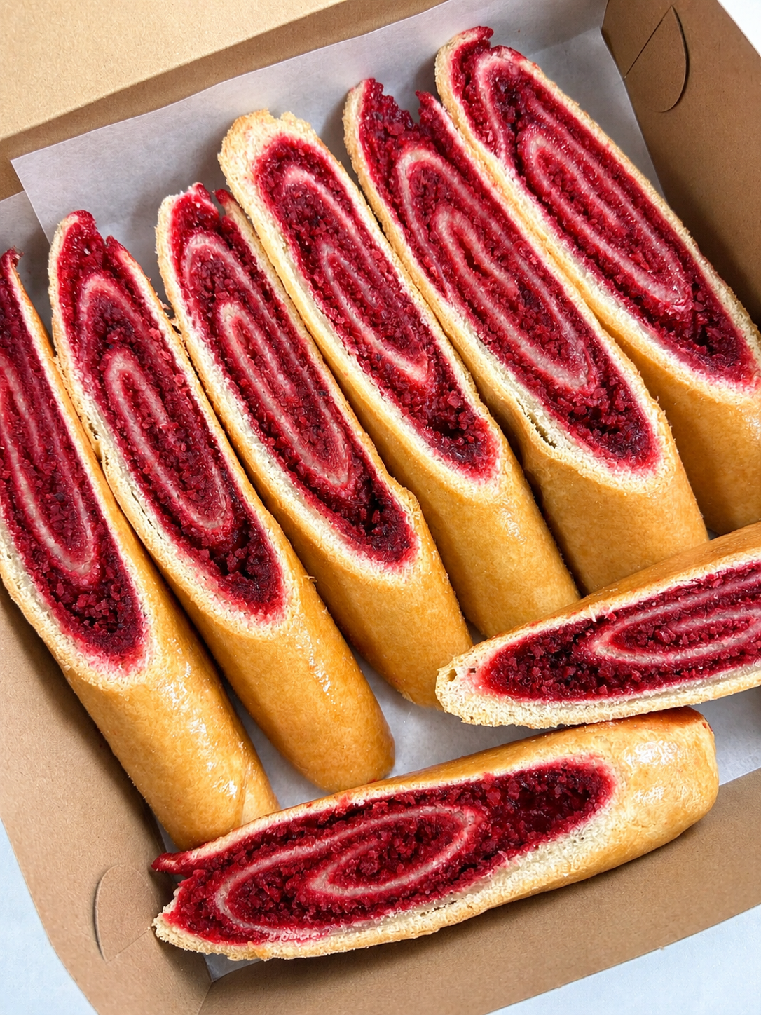 Sliced coconut roll red and white dessert pastry in a cardboard box
