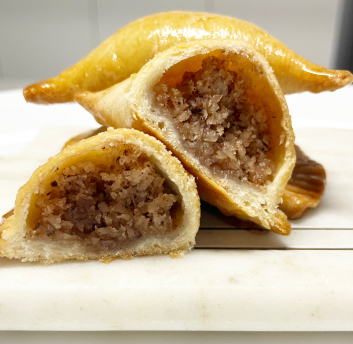 A photo showing a golden flaky crust coconut tart broken in half, with a rich coconut filling inside.